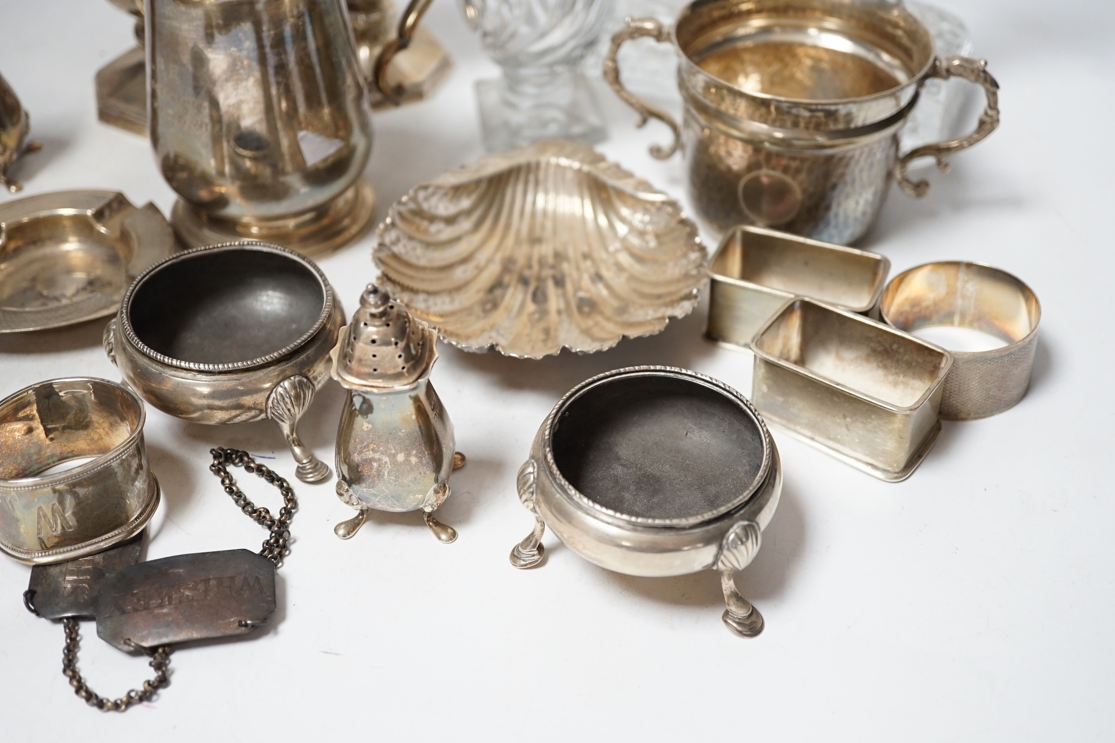 Assorted small silver including a christening mug, a planished porringer, pair of George V sugar casters, butter shell, ashtray, two mounted glass posy vases, four condiments, four napkin rings, a mounted glass cruet bot